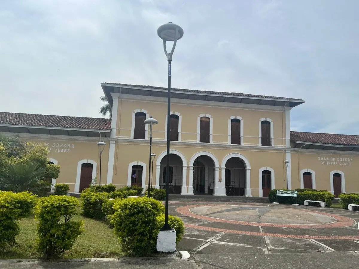Edificio de una estación del ferrocarril con jardines al frente